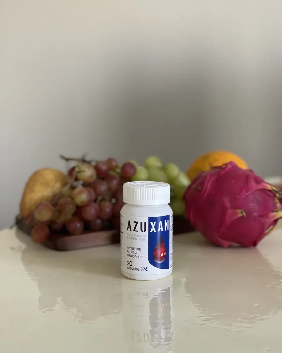 Frasco de AZUXAN junto a fruta fresca: uvas, naranja y pitaya